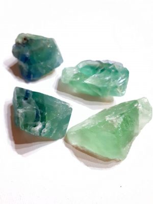 Fluorita en bruto sobre fondo blanco, piedra multicolor natural con propiedades de protección mental y armonía emocional
